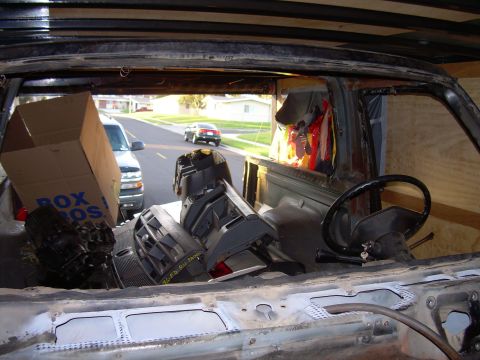 1986 Ford Bronco - View from inside a vehicle, looking out at a street with other vehicles and houses.