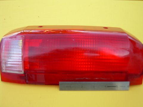 1986 Ford Bronco - A red taillight assembly is shown with a ruler for size comparison against a yellow background.