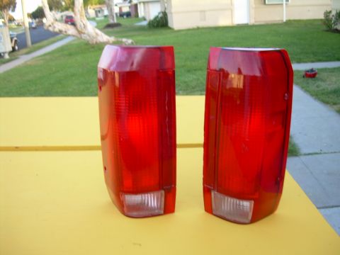 1986 Ford Bronco - A pair of red taillights are displayed on a yellow surface with a residential street in the background.