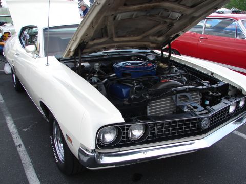 1992 Ford Taurus - Front view of a white 1970 Ford Torino GT, engine exposed, with another car in the background.