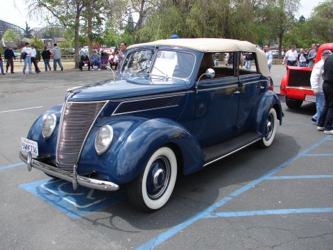 1992 Ford Taurus - A classic blue convertible, likely a 1937 model, is parked in a lot with other vehicles and spectators.