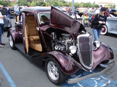 1992 Ford Taurus - A custom coupe with its hood open reveals a polished engine and tan interior at an outdoor car show.