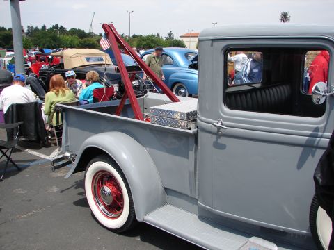 1992 Ford Taurus - A vintage tow truck is parked at an outdoor car show with other vehicles and people.