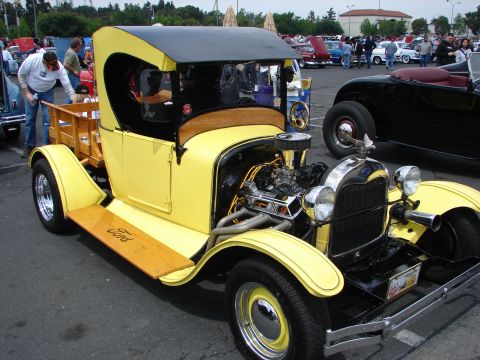 1992 Ford Taurus - A classic yellow Ford truck with a custom engine and wooden bed is displayed at an outdoor car show.