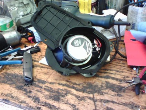 2003 Toyota Tacoma - Car speaker assembly with visible Pioneer branding and wiring, resting on a cluttered workbench.