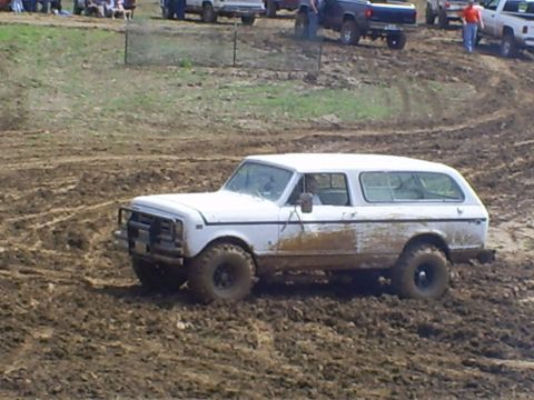 2001 Dodge 1500 - A white SUV with a brush guard drives through a muddy course with other vehicles in the background.