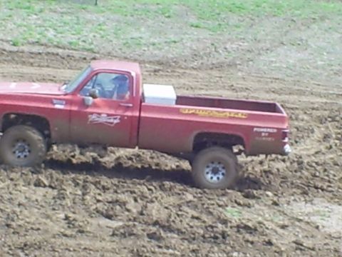 2001 Dodge 1500 - This red pickup truck is stuck in the mud, with 'Budweiser' on the door and 'POWERED BY CHEVY' on the tailgate.