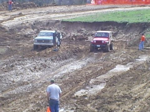 2001 Dodge 1500 - Two vehicles are driving through a muddy terrain, with spectators observing the event.