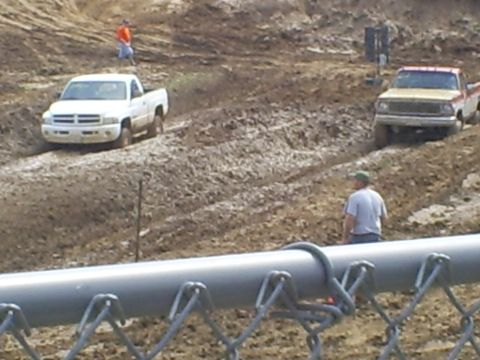 2001 Dodge 1500 - Two pickup trucks navigate a muddy off-road course during an event.