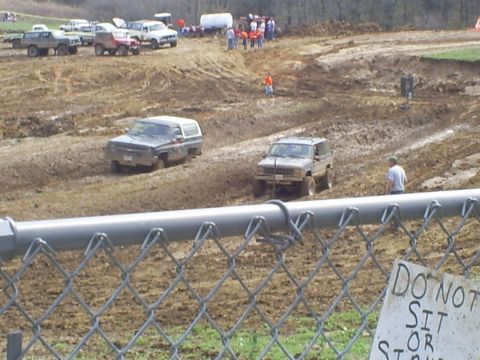 2001 Dodge 1500 - Vehicles compete in a mud race event, with spectators and other vehicles in the background.
