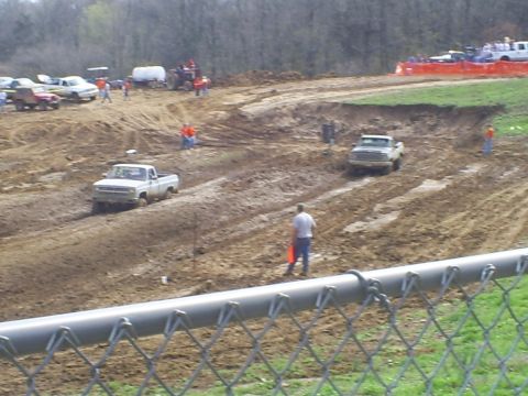 2001 Dodge 1500 - Two pickup trucks navigate a muddy track during a race event.