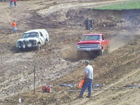 2001 Dodge 1500 - Two trucks compete in a mud race event on a dirt track.