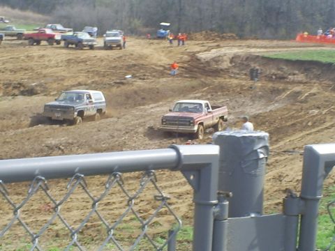 2001 Dodge 1500 - Multiple trucks and SUVs compete in a mud race event, kicking up dirt as they maneuver through the challenging terrain.