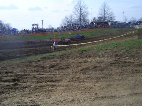 2001 Dodge 1500 - Two vehicles compete in a mud race event with spectators in the background.