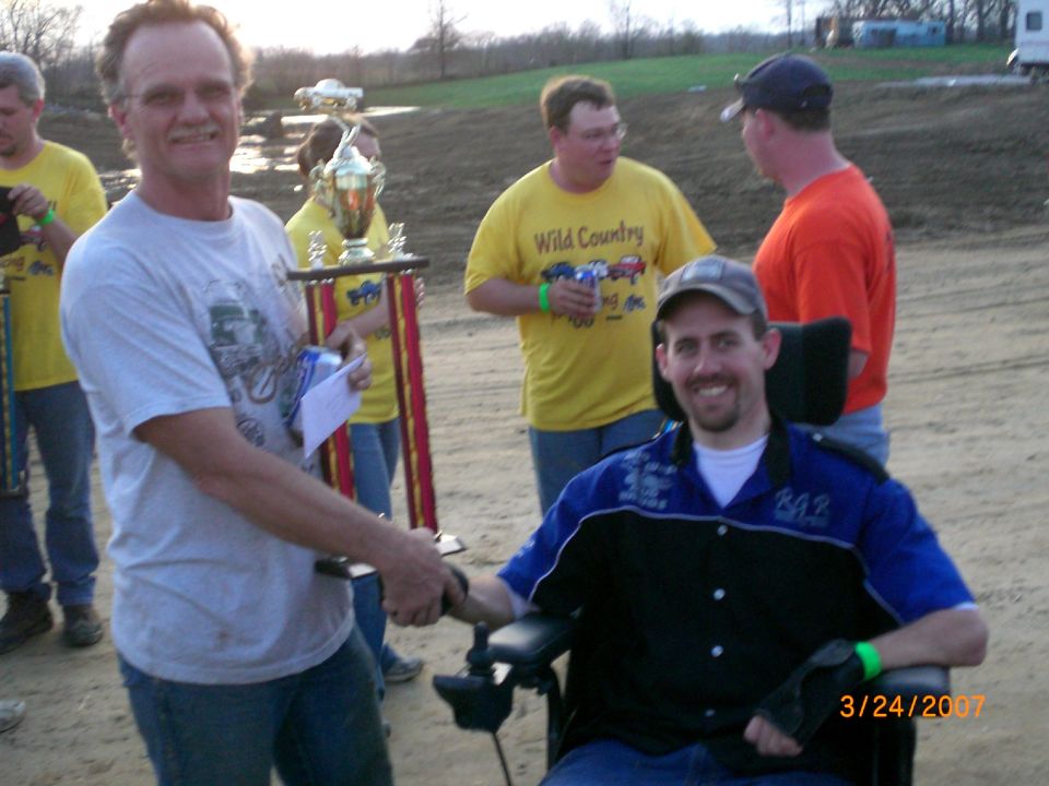 Handshake at a 2007 outdoor mud race trophy presentation on a dirt track