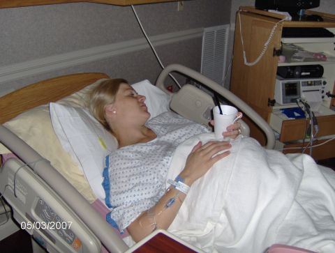 1978 Ford Bronco - A woman rests in a hospital bed, holding a cup and surrounded by medical monitoring equipment.
