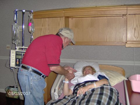1978 Ford Bronco - A man visits a woman in a hospital room, holding her hand as she rests in bed.