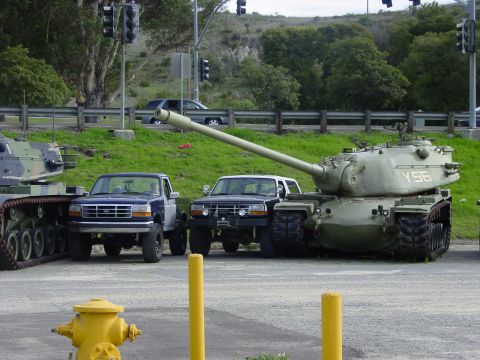 1994 Ford Bronco - Two Ford F-150 pickup trucks are parked next to a military tank.