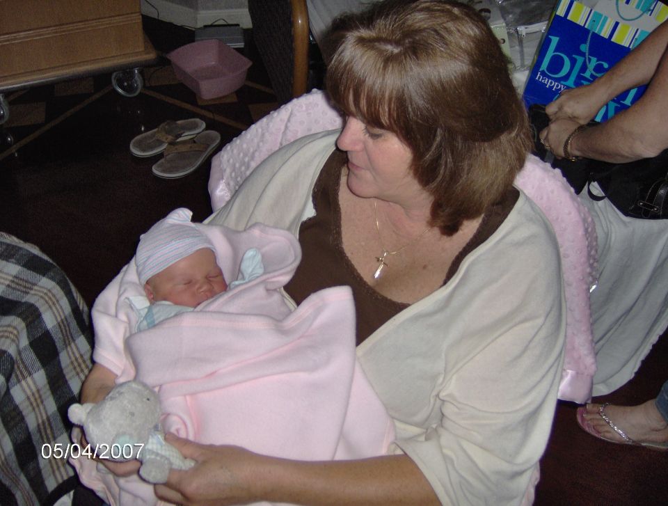 Woman holding a newborn baby wrapped in a pink blanket