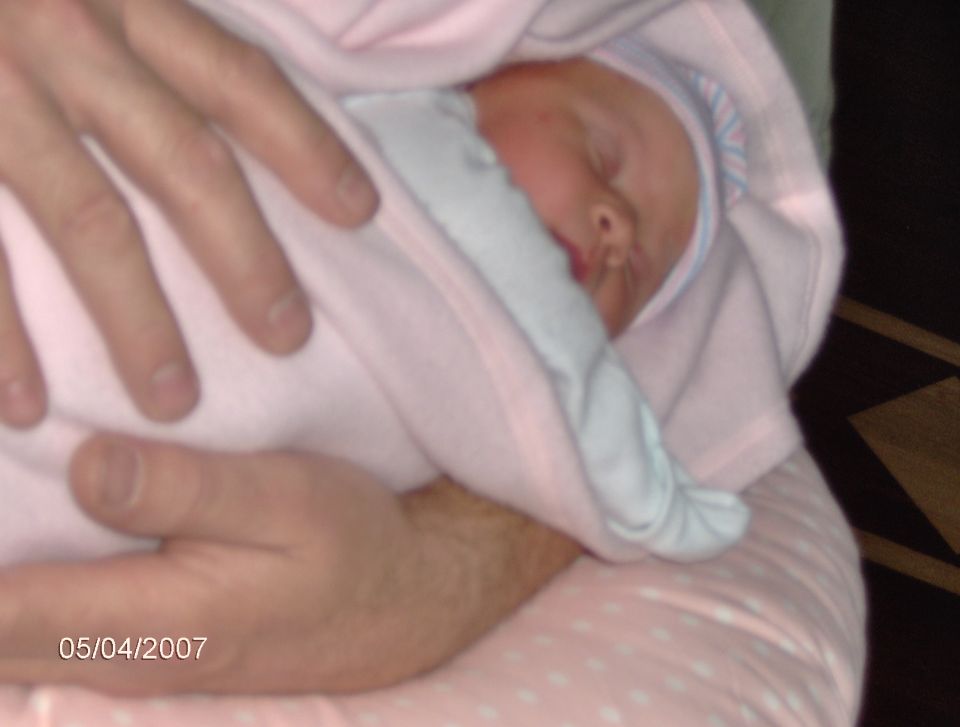 Baby sleeping, wrapped in pink blanket. Date stamp reads 05/04/2007
