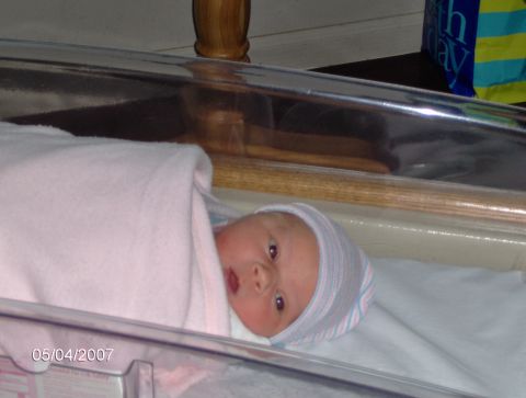 1978 Ford Bronco - A newborn baby is swaddled in a pink blanket and wearing a hospital hat, lying in a bassinet.