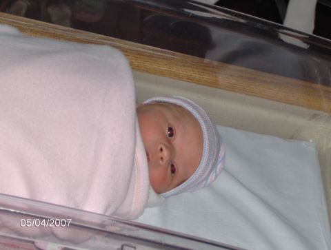 1978 Ford Bronco - A newborn baby is swaddled in a pink blanket and wearing a hospital hat in a bassinet.