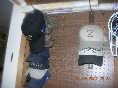 1991 Ford F-150 - A collection of baseball caps hangs on a pegboard, displaying various logos and text, including 'Watts Bar SGRP' and 'Marlin'.