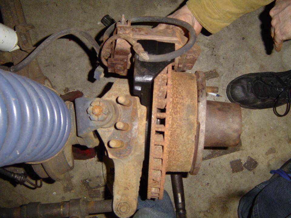Rusty front axle hub and brake assembly on a garage floor