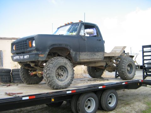 1990 Ford Bronco - This heavily modified pickup truck, likely from the 1970s, is loaded onto a flatbed trailer.