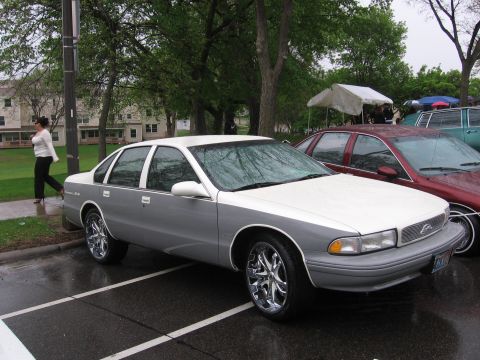 1998 GMC Sierra 1500 - A two-tone sedan is parked in a lot next to other vehicles on a rainy day.