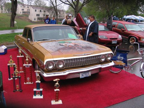 1998 GMC Sierra 1500 - A gold 1963 Chevrolet Impala is displayed with trophies, while other vehicles are visible in the background.
