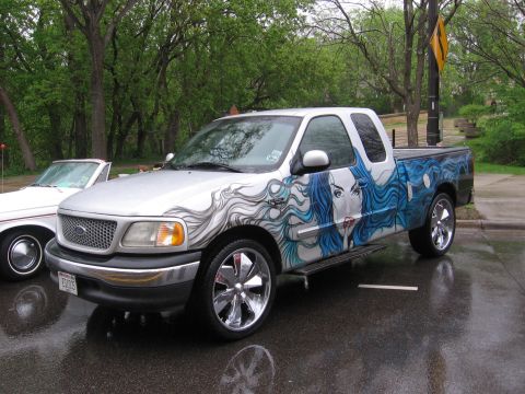 1998 GMC Sierra 1500 - This pickup truck features a striking custom mural art on its side, depicting a woman's face with flowing blue hair.