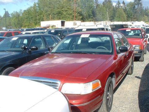 2000 Ford Crown Victoria - A red 2000 Ford Crown Victoria is parked in a lot filled with other cars and trucks.