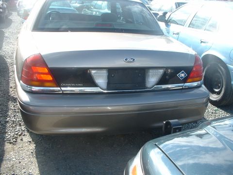2000 Ford Crown Victoria - The rear of a tan 2000 Ford Crown Victoria is visible, parked next to another vehicle.