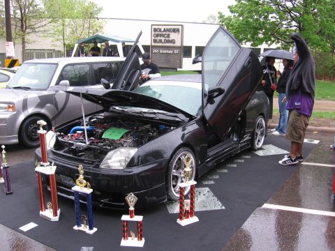 1998 GMC Sierra 1500 - Modified coupe with custom doors and engine display at an outdoor event, with a silver SUV nearby.