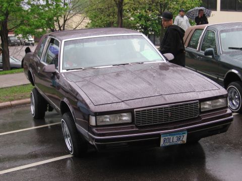 1998 GMC Sierra 1500 - A maroon coupe with a custom hydraulic suspension is parked next to another vehicle.