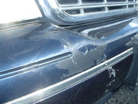 2000 Ford Crown Victoria - Damaged blue car bumper shows significant paint peeling and scratches.