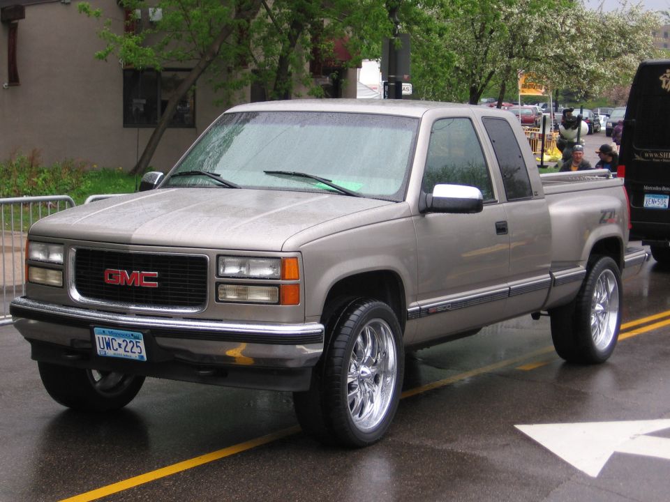 Tan GMC pickup truck with chrome wheels and a stepside bed. License plate is UWC-225