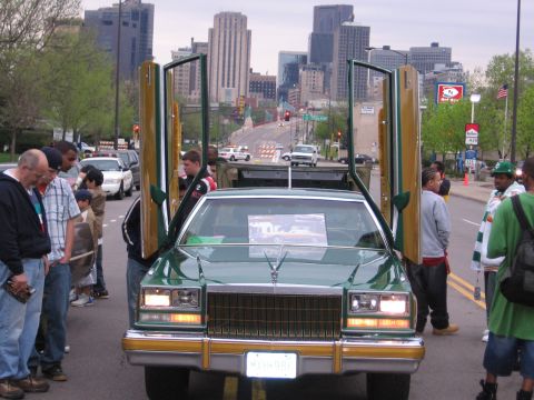 1998 GMC Sierra 1500 - A green sedan with custom gullwing doors is on display with onlookers gathered around.