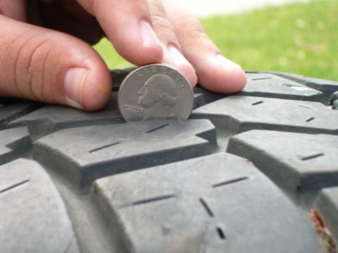1986 Ford Bronco - Checking tire tread depth with a quarter coin.