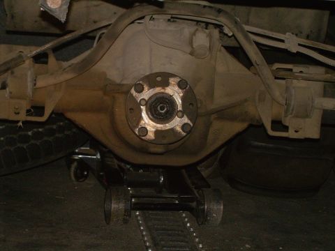 1986 Ford Bronco - Close-up view of a vehicle's rear axle differential, supported by a floor jack.