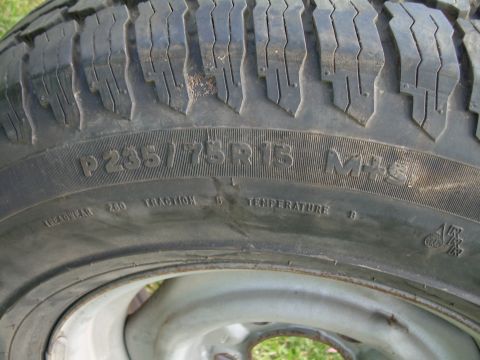 1986 Ford Bronco - A close-up view of a tire shows the size P235/75R15 and M+S markings.