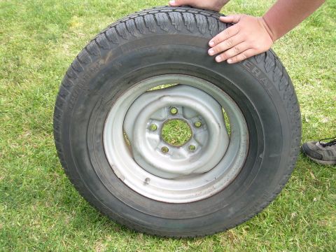 1986 Ford Bronco - A spare tire and rim are shown, with a person's hands holding the tire.