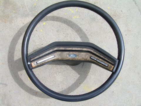 1986 Ford Bronco - This Ford steering wheel features wood grain trim and cruise control buttons, likely from an older model truck or SUV.
