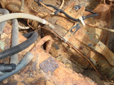 1996 Ford Bronco - Close-up view of heavily rusted undercarriage components, including hoses and wiring, suggesting significant wear or disuse.