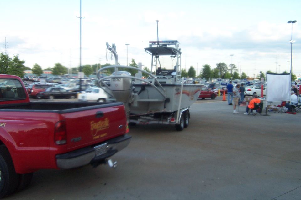 Red pickup truck towing a boat on a trailer in a parking lot