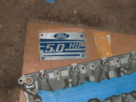 1990 Ford Ranger - Ford 5.0 HO emblem plate and engine block part shown on a workbench.