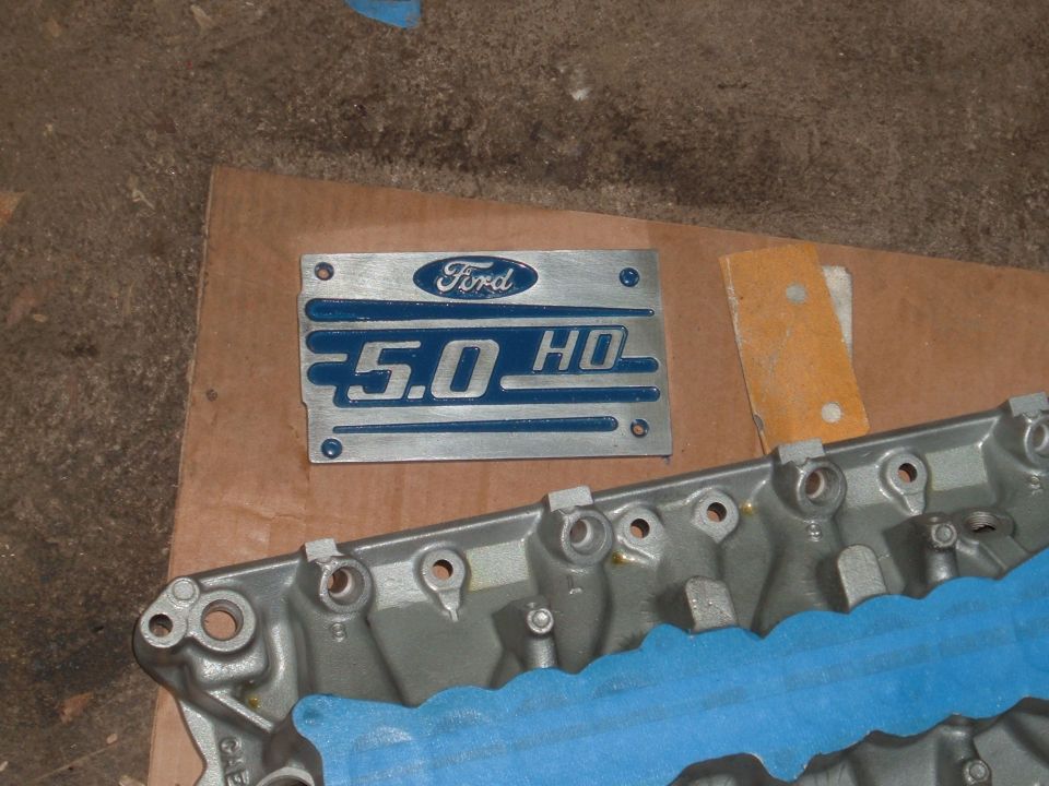 Ford 5.0 HO emblem plate and part of an engine block with blue tape