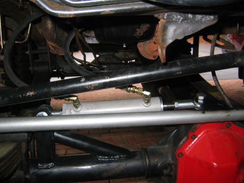 1979 Ford Bronco - Underside view of a vehicle's steering system, focusing on a hydraulic assist cylinder.