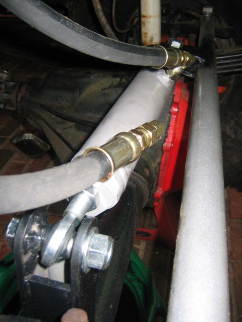 1979 Ford Bronco - Close-up view of a hydraulic steering assist cylinder and hoses, likely part of a custom modification or repair.